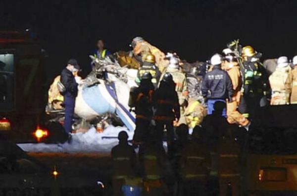 Firefighters inspect a part of the wreckage of the burnt Japan Airlines plane on the runway of Haneda airport. Picture: Kyodo News via AP