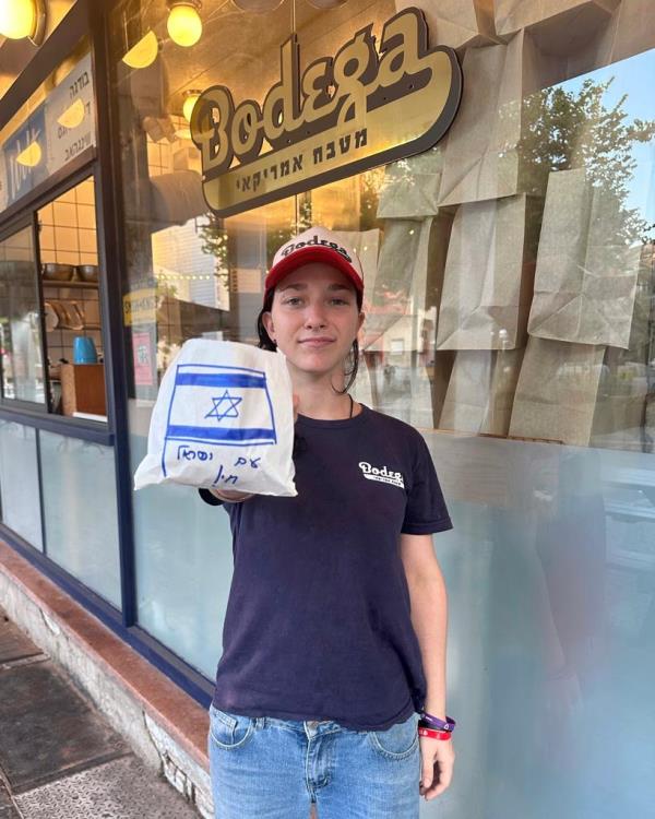 Girl holding out a burger wrapped in paper with a note