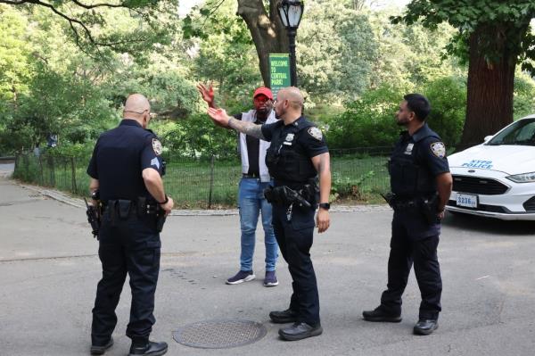 NYPD Central Park Precinct officers conversing with victim Johnny Edwards about a robbery at gunpoint near a lake in the park